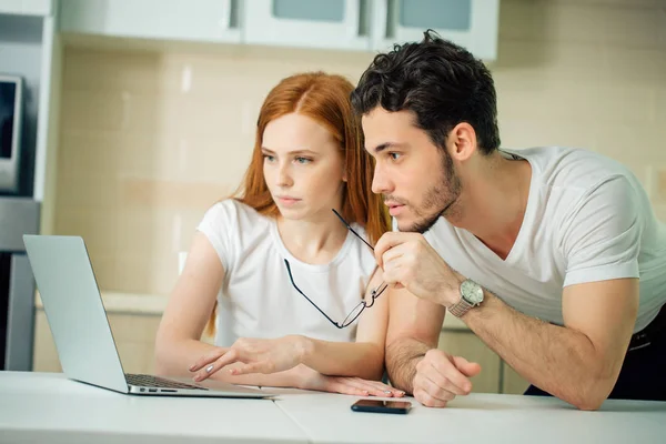 Casal navegando internet juntos sentado à mesa e sorrindo e ler tela — Fotografia de Stock