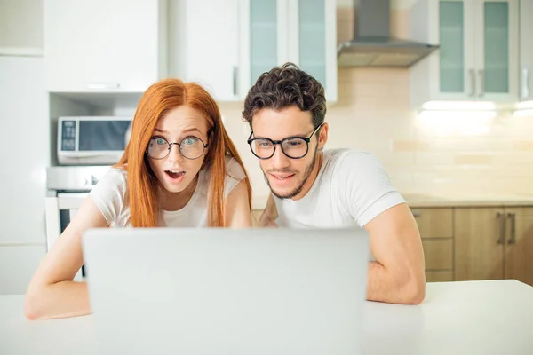 Erstauntes Paar mit offenem Mund online mit Laptop im heimischen Wohnzimmer — Stockfoto