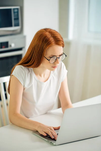 Empresária ruiva concentrada trabalhando em laptop em escritório moderno brilhante — Fotografia de Stock