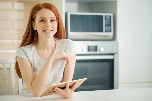 Happy young woman holding tablet and looking at camera — Stock Photo, Image
