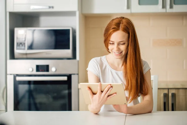 Счастливая женщина, работающая дома с цифровым планшетом на столе — стоковое фото