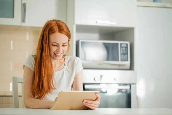 Счастливая женщина, работающая дома с цифровым планшетом на столе — стоковое фото
