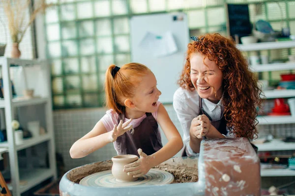 Redhead mother and her child daughter moulding with clay on pottery wheel — Stock Photo, Image