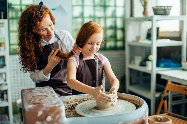 Руда мати і її дочка формуються глиною на керамічному колесі — стокове фото