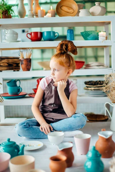 Дівчина wih багато чашок з глини сидить в керамічній студії — стокове фото