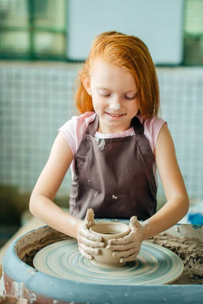 Vöröshajú gyerek sculpts clay pot. workshop a modellezés a fazekasok kerék. — Stock Fotó