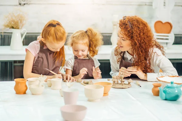 Roodharige moeder en twee dochter schimmel met klei, aardewerk kinderen — Stockfoto