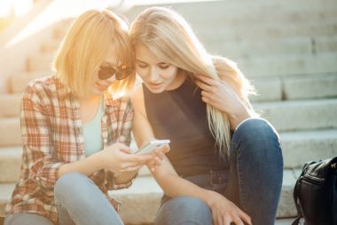 İki güzel öğrenci medya içeriği Park akıllı telefon bir satır izlerken