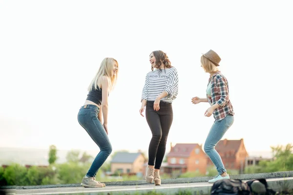 Three happy joyful young women jumping and laughing together at park — Stock Photo, Image
