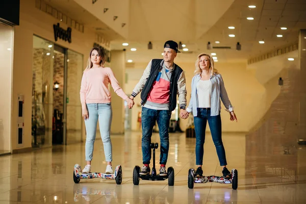 Homme et deux femme chevauchant sur Hoverboard dans le centre commercial — Photo
