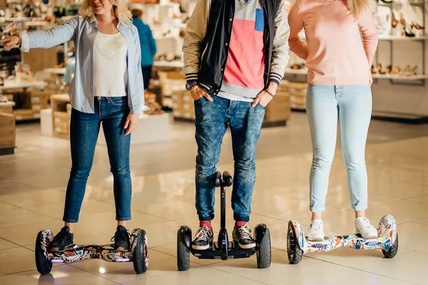 Homem e duas mulher equitação no hoverboard no shopping — Fotografia de Stock