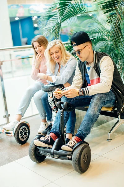 Grupo de pessoas no hoverboard scooter elétrico sentado no banco e usando telefone — Fotografia de Stock