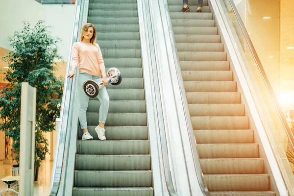 Flicka med hoverboard rider på rulltrappan — Stockfoto