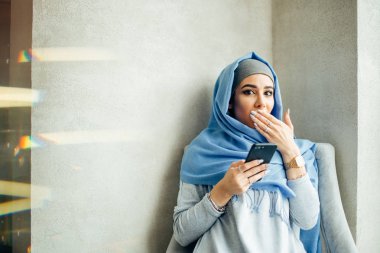 Oturma ve cep telefonu tutan genç kadın