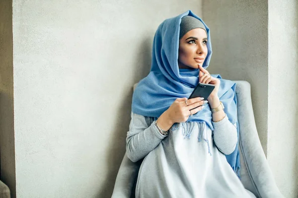 Mensajería de mujer musulmana en un teléfono móvil en la cafetería — Foto de Stock