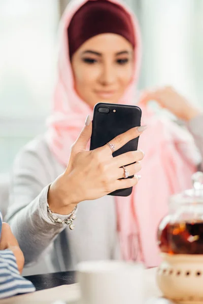 Портрет молодой привлекательной женщины в хиджабе, делающей селфи на смартфоне — стоковое фото