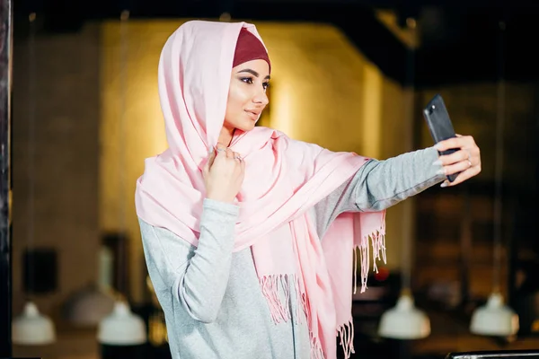 Арабская мусульманка делает селфи с телефоном в кафе — стоковое фото
