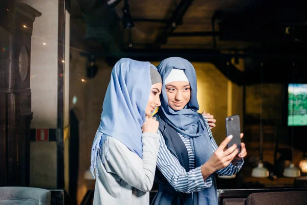 Dos feliz joven musulmana mujer tomar autorretrato con teléfono en la cafetería — Foto de Stock