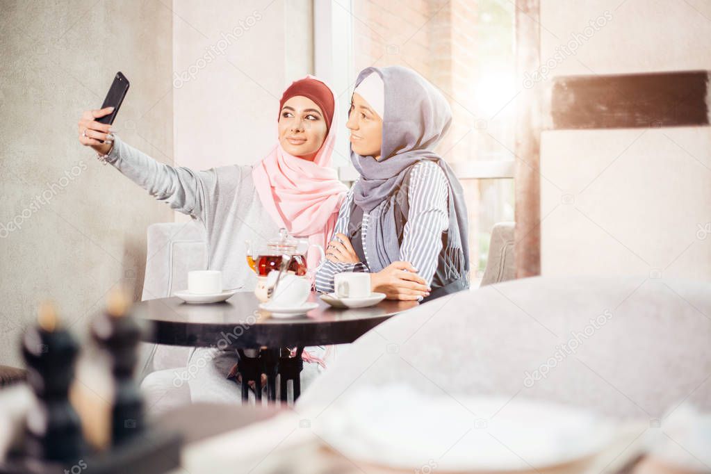 young beautiful muslim woman taking a self portrait with camera phone