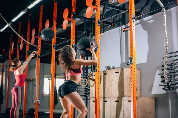 Dos mujeres lanzan bolas de medicina en el gimnasio de fitness — Foto de Stock