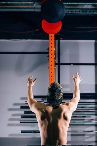 Perfil de un joven atleta agachado haciendo ejercicios de bolas de pared en el gimnasio — Foto de Stock