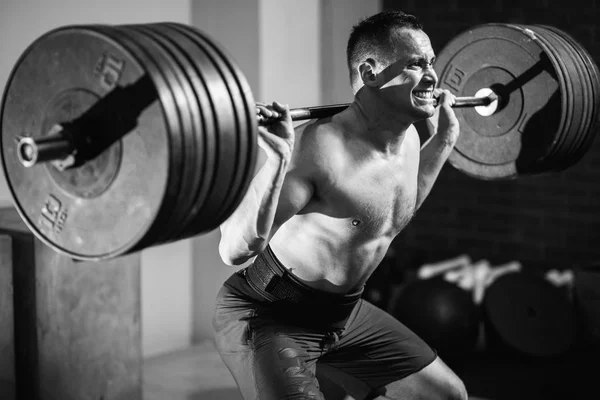 Musculoso hombre entrenamiento sentadillas con barras en los hombros — Foto de Stock