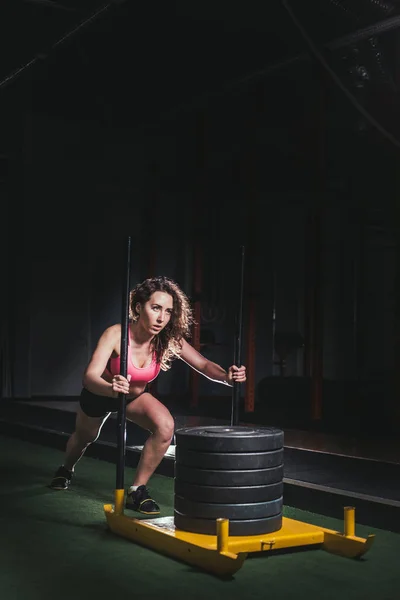 Sled push vrouw duwen gewichten workout oefening — Stockfoto