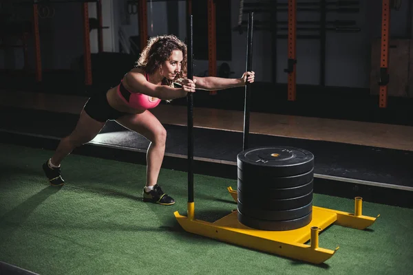 Trineo empuje mujer empujando pesos entrenamiento ejercicio —  Fotos de Stock