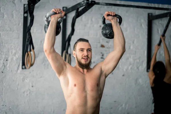 Homem levantando dois kettlebell exercício no ginásio — Fotografia de Stock