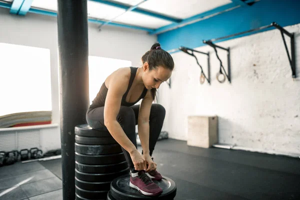 Belle femme attachant lacets à la salle de gym — Photo