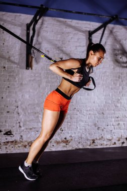 Trx kavramı. Bayan süspansiyon antrenörü askı yardımıyla kasları egzersiz