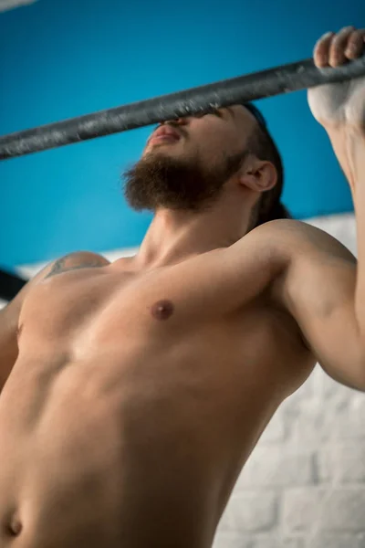 Atleta fitness muscolare modello maschile tirando su sulla barra orizzontale in una palestra — Foto Stock