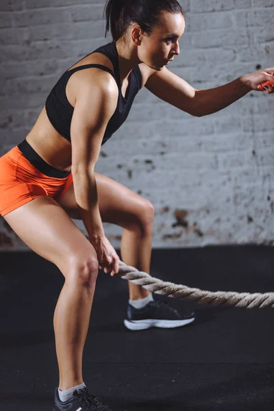 Αθλητική γυναίκα κάνει κάποια cross fit ασκήσεις με μάχη σχοινί εσωτερική — Φωτογραφία Αρχείου