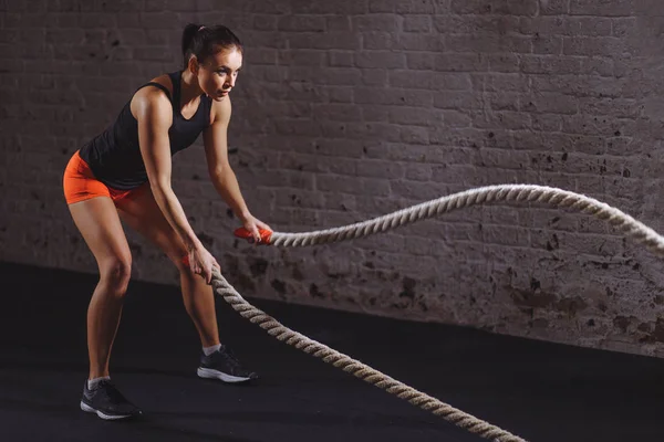 Mujer atlética haciendo ejercicios de cuerda de batalla en el gimnasio — Foto de Stock