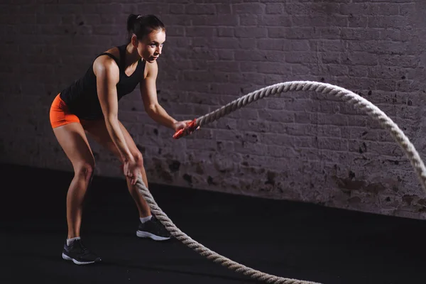 Mulher atlética fazendo exercícios de corda de batalha no ginásio — Fotografia de Stock
