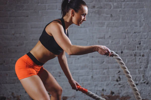 Mulher treinando com corda de batalha em cross fit ginásio — Fotografia de Stock