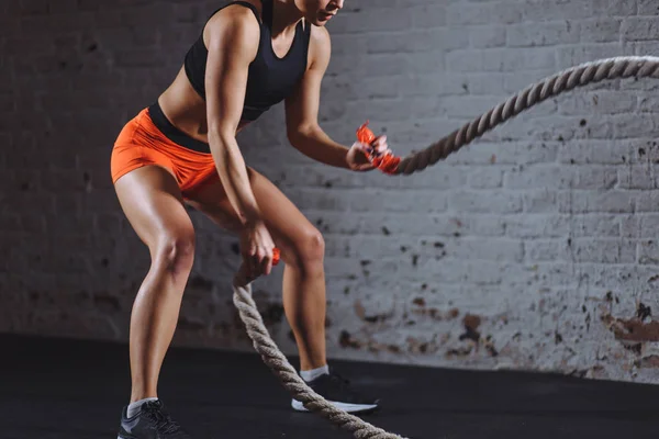 Close up photo of Athletic woman doing battle rope exercises at gym — Stock Photo, Image