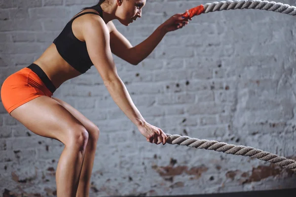Mulher treinando com corda de batalha em cross fit ginásio — Fotografia de Stock