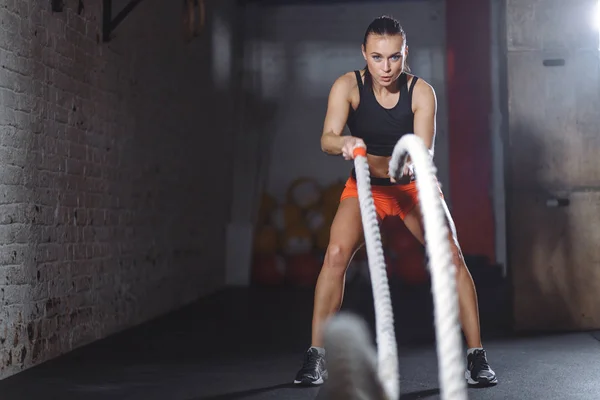 Attraktive junge fitte und durchtrainierte Sportlerin, die mit Kampfseilen trainiert — Stockfoto