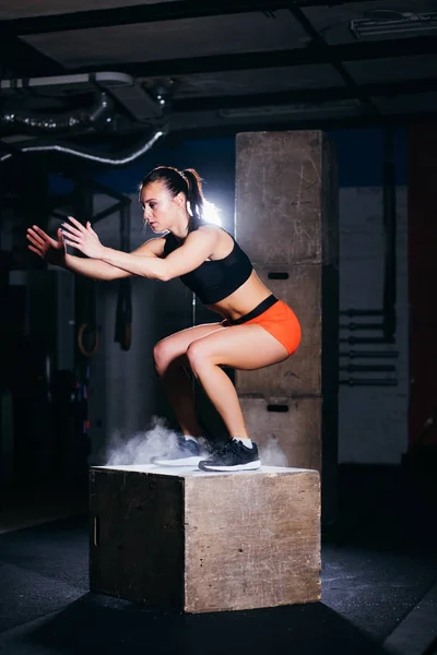 Mujer saltando caja. Mujer de fitness haciendo entrenamiento de salto de caja en el gimnasio de cross fit . — Foto de Stock