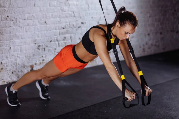 Kvinnor gör push ups utbildning vapen med trx remmar i gymmet — Stockfoto