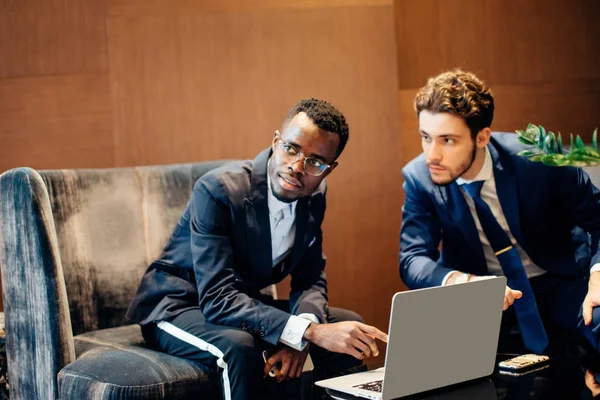 Zakenman met behulp van laptop te bespreken van informatie met collega in moderne kantoren — Stockfoto