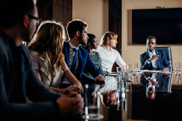 black male boss talking to business team in conference room