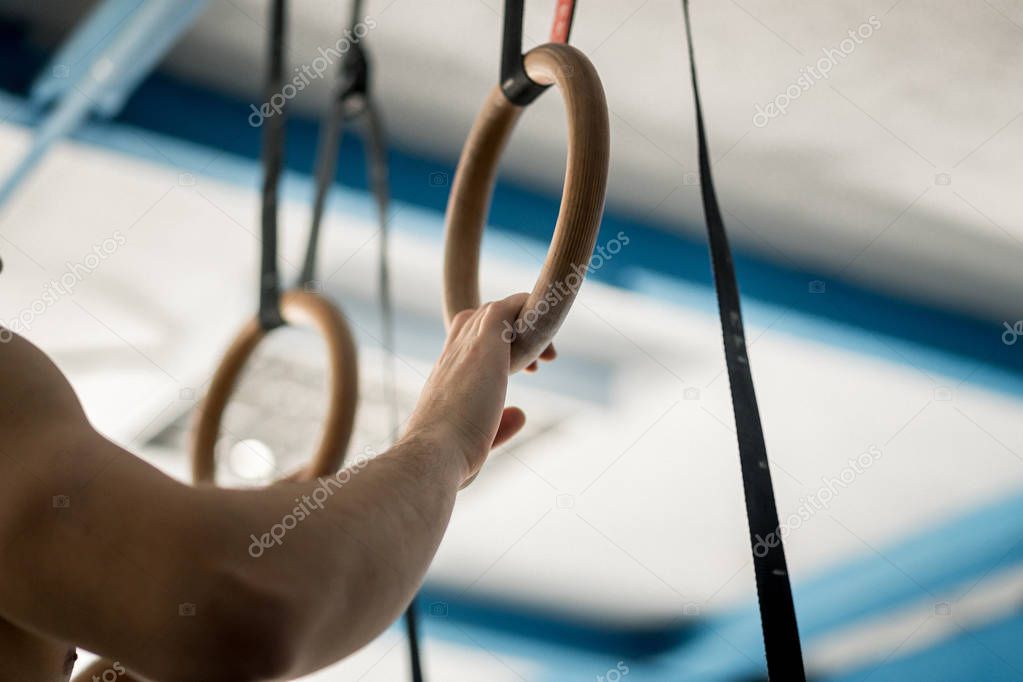 Muscle-up exercise athletic man doing intense workout at gym on gymnastic rings