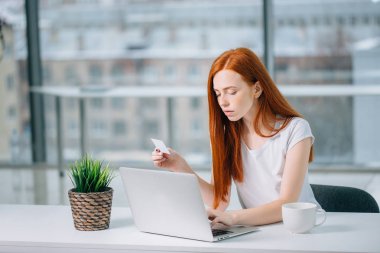 İnternetten bilgisayar ve kredi kartıyla alışveriş yapan kız.