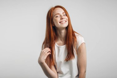 Beyaz arka plan üzerinde kırmızı saçları dokunmadan Kapalı gözlerle gülümseyen kız