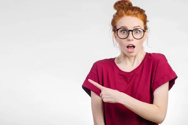 Surprised girl showing empty copy space with her finger white background — Stock Photo, Image