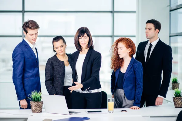 Lächelnde weibliche und gut aussehende männliche Kollegen, die am Tisch sitzen und auf Laptop schauen — Stockfoto