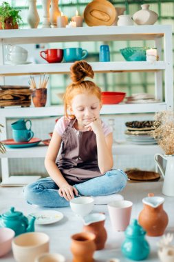 Kız wih kil çömlek stüdyoda oturan fazla bardak yapılmış