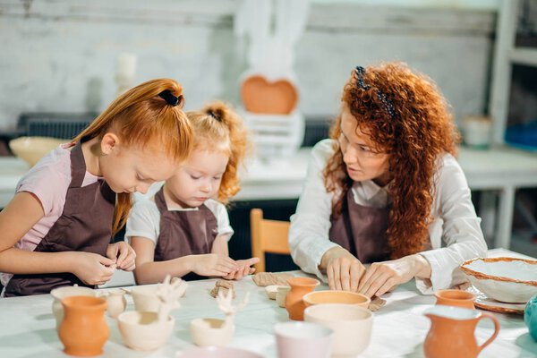 redhead Mother and kid daughter at home molded from clay and play together